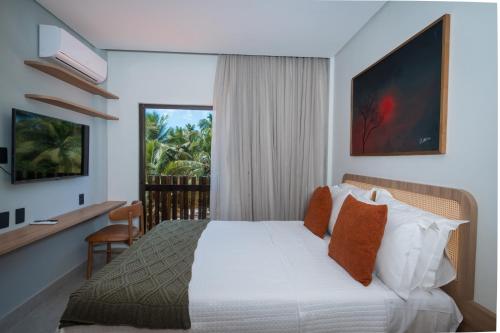 a bedroom with a bed and a desk and a window at Be caju flats in Barra Grande