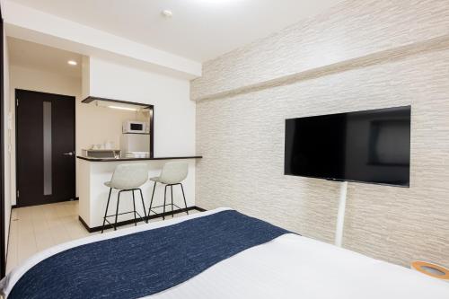 a hotel room with a bed and a flat screen tv at SPAZIO 1 Canal Hakata Annex in Sumiyoshi