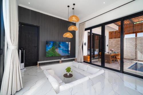 a living room with a white couch and a tv at Villa Toograss close to Black Sand Beach in Keramas