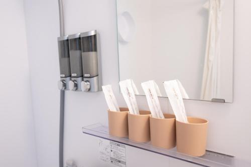 a shelf with four brown and white toothbrushes at NEW OPEN! HOTEL Kozafornia in Okinawa City