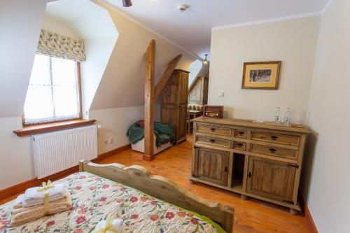 a bedroom with a bed and a dresser and a window at Folwark Hutta in Suwałki