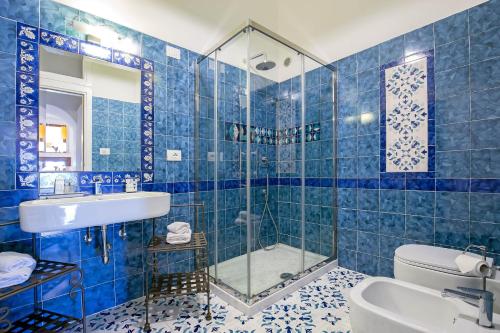 een blauwe betegelde badkamer met een wastafel en een douche bij Starhost - CASA BETTINA in Vietri