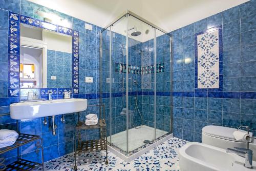 a blue tiled bathroom with a sink and a shower at Starhost - CASA BETTINA enchanting seaview in Vietri sul Mare