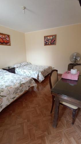 a room with two beds and a table at La casa de Manuel in Lunahuaná