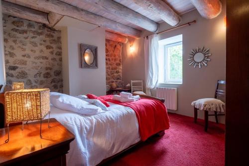 a bedroom with a large bed with a red carpet at Gîte oya in Chaudeyrac