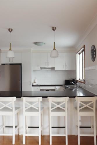a kitchen with a black counter and white cabinets at Beside the Seaside Gerroa Dual Family Living in Gerroa