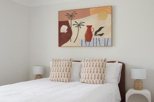 a bedroom with a white bed with two pillows at Beside the Seaside Gerroa Dual Family Living in Gerroa