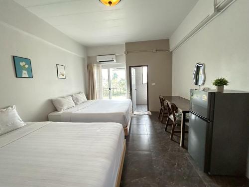 a hotel room with two beds and a table and a refrigerator at Comfy hotels Suvarnabhumi in Suvarnabhumi Airport