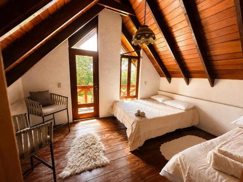 a bedroom with two beds and a chair and windows at Valle Verde Lodge - Bosque in Samaipata