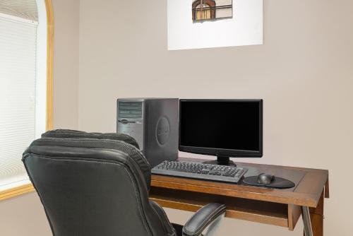 a desk with a computer monitor and a keyboard and mouse at Super 8 by Wyndham Athabasca AB in Athabasca