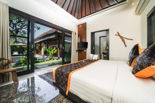 a bedroom with a bed and a large window at Katala Suites and Villas in Sanur
