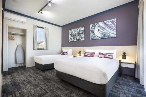 two beds in a hotel room with purple walls at Nightcap at Wanneroo Tavern in Wanneru