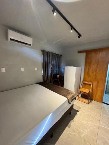 a bedroom with a bed and a refrigerator and a chair at Pousada Bonetti Quarto 11 in Santa Rosa