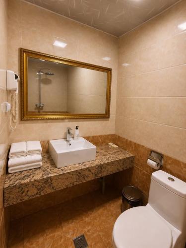 a bathroom with a sink and a toilet and a mirror at Kentavr Hotel in Ulaanbaatar
