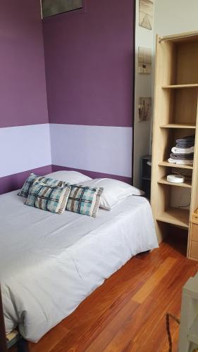 a bedroom with a bed with a purple wall at RESIDENCE HERMITAGE LE TOUQUET in Le Touquet-Paris-Plage