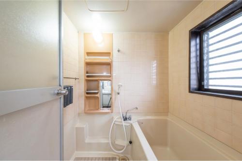 a bathroom with a bath tub and a window at en stay001 in Osaka