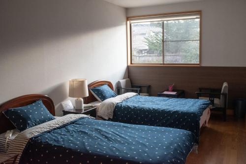 a room with two beds with blue sheets and a window at なかつい陣屋 in Fujita