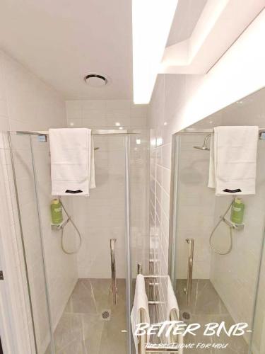 a bathroom with a shower with towels and a sink at The Elegant Corner in Wellington