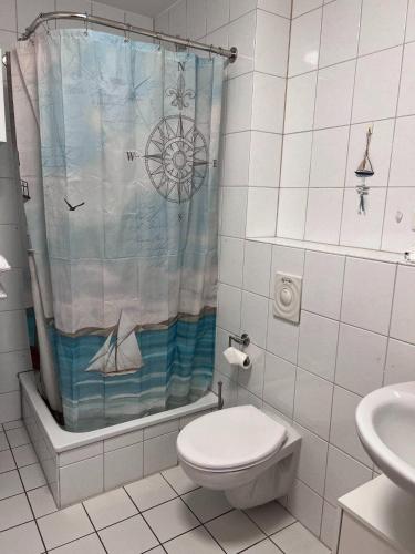 a bathroom with a shower curtain with a toilet and a sink at Lachmoewe in Orth