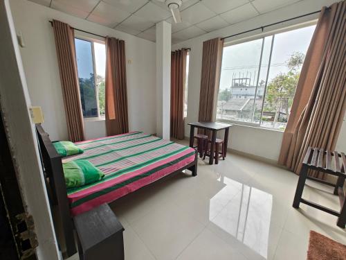 a bedroom with a bed and a table and windows at Harry Inn in Negombo