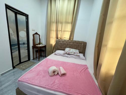 a bedroom with a pink bed with two towels on it at DGarden Homestay in Kuala Terengganu