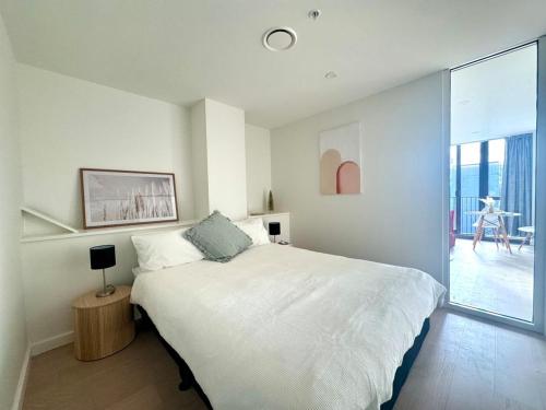 a white bedroom with a bed and a large window at The Urban Nest 613 in Wellington