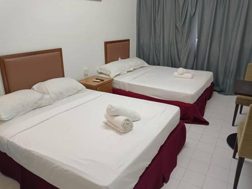 two beds in a hotel room with towels on them at VKB Ferringhi Styles Penang formerly Grand Star Hotel in Batu Ferringhi