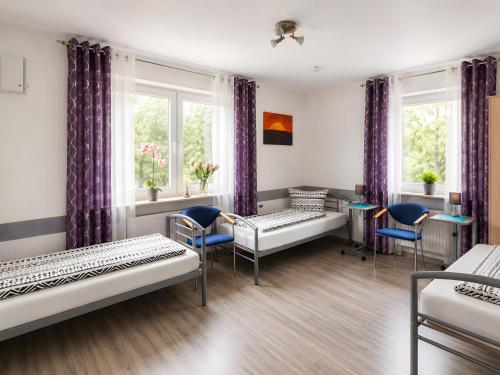 a room with beds and chairs and windows at Ferienwohnung Gartenblick in Laupheim