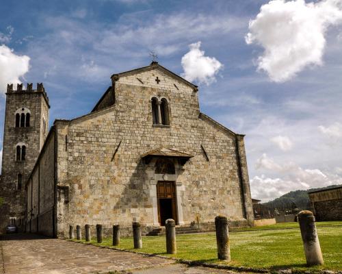an old stone church with a tower on a field at Hotel Lungomare in Lido di Camaiore