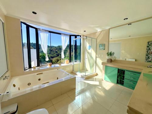 a large bathroom with a tub and a large window at Pousada Casa Florinda in Teresópolis