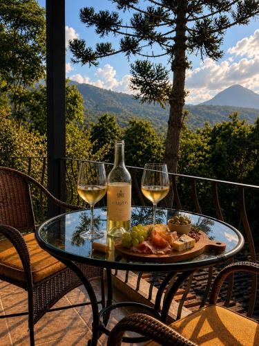 a table with two glasses of wine and a plate of food at Pousada Casa Florinda in Teresópolis