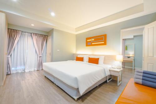 a bedroom with a large white bed and a window at Koon Hotel Sukhumvit in Bangna