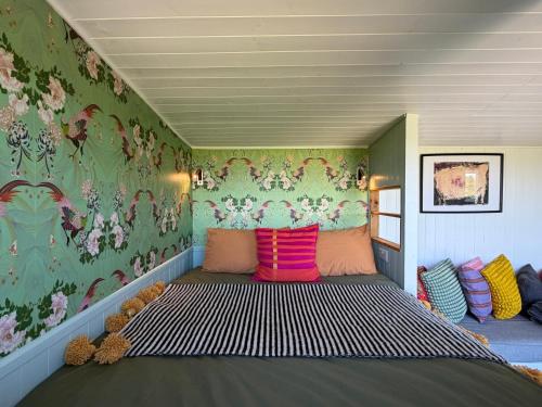 a bedroom with a large bed with colorful pillows at Tŷ Ni Tiny Houses in Bridell