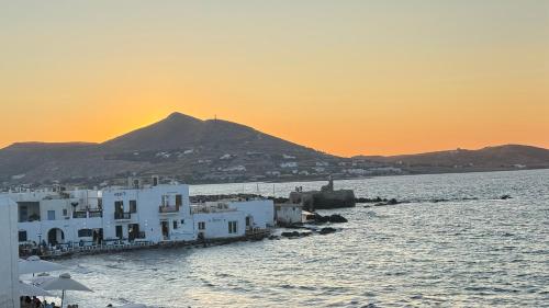 a group of white buildings on the water with a mountain at Eugene Sea Side Suite in Naousa