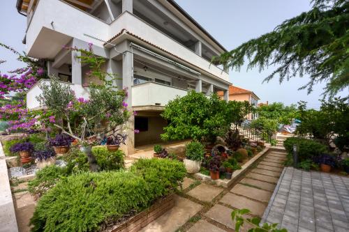 a house with flowers and plants in front of it at Pool & Garden Apartment Bakija - Happy Rentals in Pakoštane