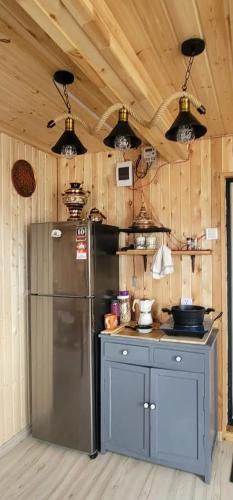 a kitchen with a stainless steel refrigerator and wooden walls at Mothers Modern Lakeside Cabin in Khyaktil