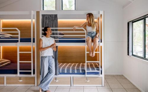 a man and a woman standing in front of bunk beds at Wake Up! Byron Bay in Byron Bay