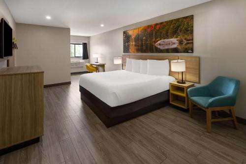 a hotel room with a bed and a blue chair at Days Inn by Wyndham Moosic in Moosic
