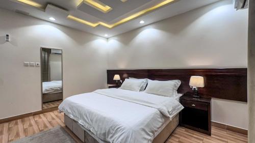 a bedroom with a large bed and a mirror at قصر لوماج - احد رفيدة in Ahad Rafidah