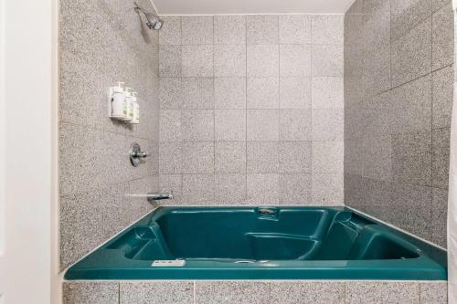 a bathroom with a blue tub in a shower at Days Inn by Wyndham Valemount in Valemount
