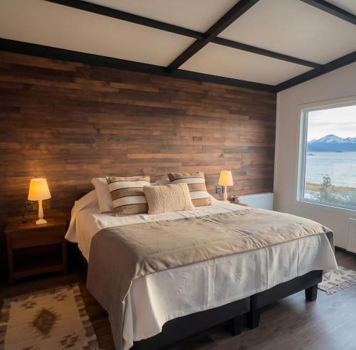 a bedroom with a large bed with a wooden wall at Cabañas AlSur Patagonia in Puerto Natales