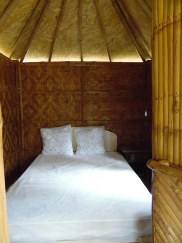 a bed in a wooden room with white sheets at CAMPING LES PAILLOTES in Payrac
