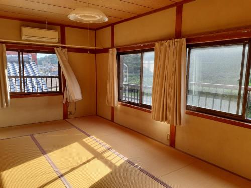 an empty room with two windows and a view at 民宿なかやま in Kushimoto