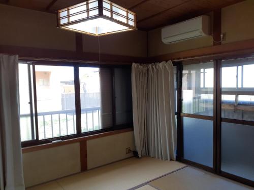 a room with large windows and a chandelier at 民宿なかやま in Kushimoto