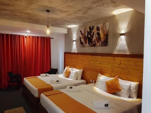 a hotel room with two beds and a red curtain at Mount End Hotel Nuwara Eliya in Nuwara Eliya