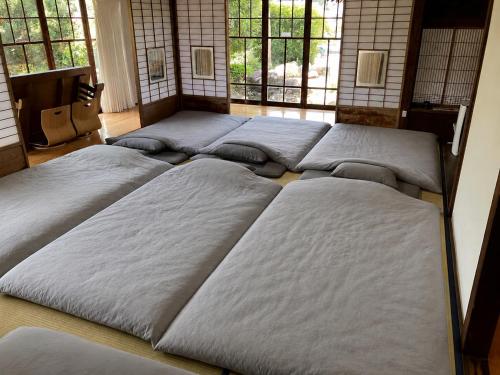 a group of beds in a room with windows at 見晴らしの宿 Guest House景 in Kumamoto