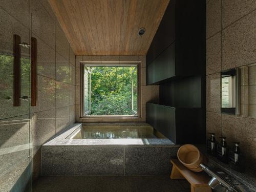 a bathroom with a large tub with a window at OTARU RETREAT KURAMURE by Onko Chishin in Otaru