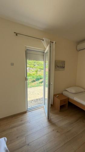a room with a bed and a sliding glass door at Guesthouse Feel Lake in Virpazar