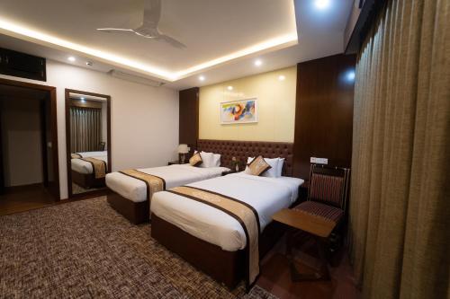 a hotel room with two beds and a mirror at Paragon Hotel & Resort in Sreemangal