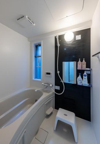 a bathroom with a tub and a stool in it at Kame Ame House in Kameoka